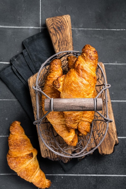 Croissants recién horneados sobre tabla de cortar de madera Fondo negro Vista superior