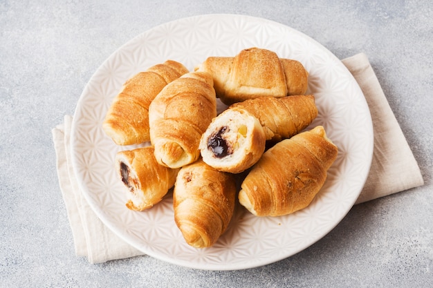 Croissants con relleno de chocolate sobre un fondo gris de la placa.