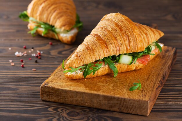 Croissants-Sandwiches mit Lachsfisch-Frischkäse und Rucola auf einem Holztisch