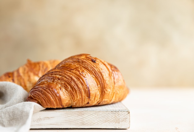 Croissants sobre tabla de cortar de madera, superficie de hormigón ligero