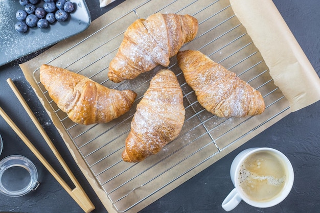 Croissants sobre una tabla de madera Fruta y café en los alrededores Desayuno francés