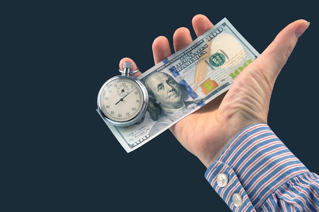 Foto cronómetro mecánico y dólares en la mano del hombre precisión a tiempo parcial para el tiempo de negocios y finanzas