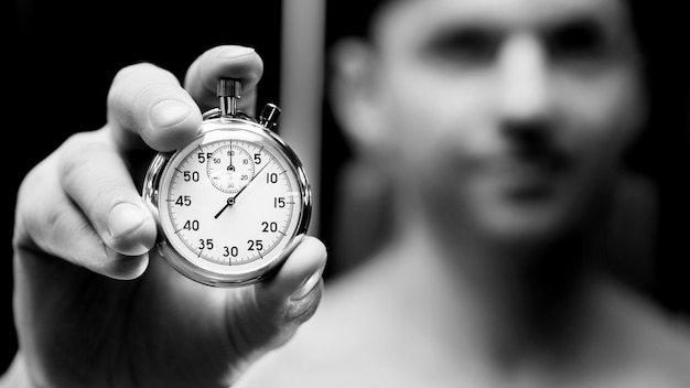 Cronómetro mecánico en una mano. Atleta hombre con reloj. Concepto de fitness y deporte