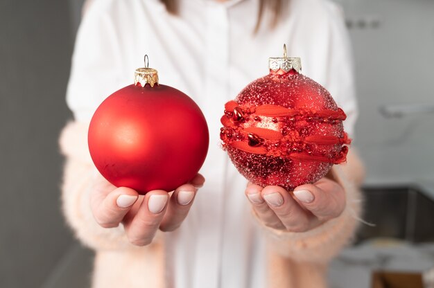 Crop-Ansicht einer Frau, die rote Weihnachtskugeln in den Händen hält. Magische Zeit.