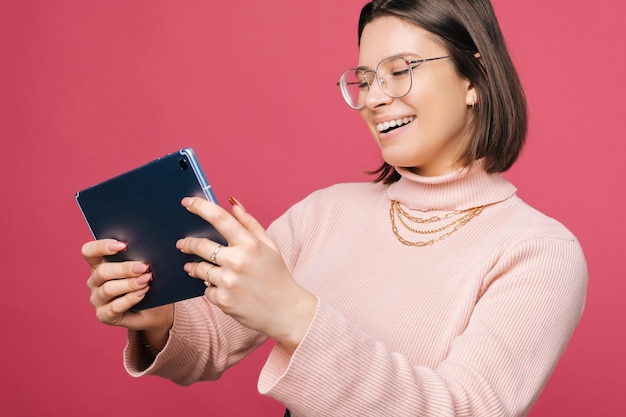 Crop-Porträt einer Frau, die auf einem digitalen Tablet spielt und dabei breit lächelt