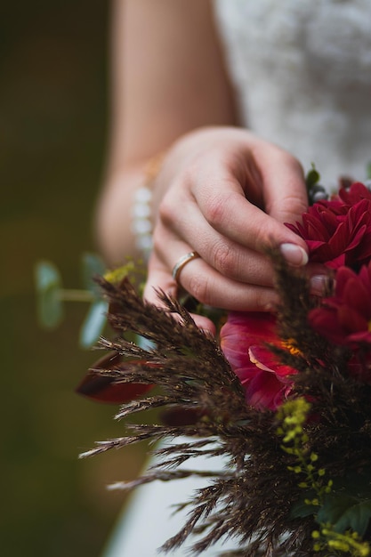 Crop verschwommene Frau in weißem Hochzeitskleid mit erstaunlich lebendigem Blumenstrauß und berührenden Blütenblättern