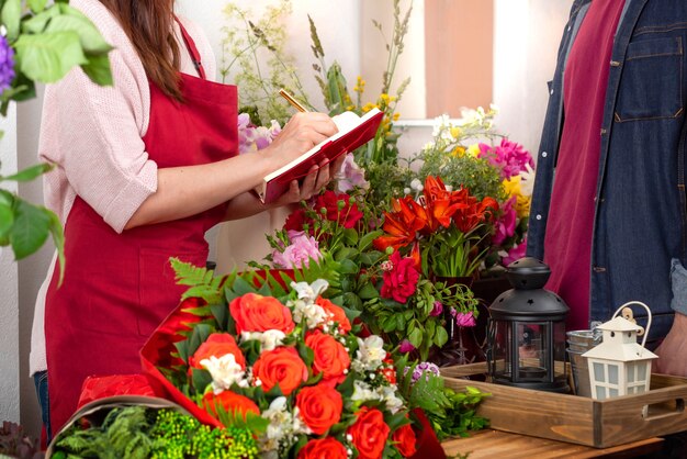 Crop-View-Saller von Blumen, die die Bestellung annehmen. Floristisches Geschäft. Arrangement von Blumensträußen.