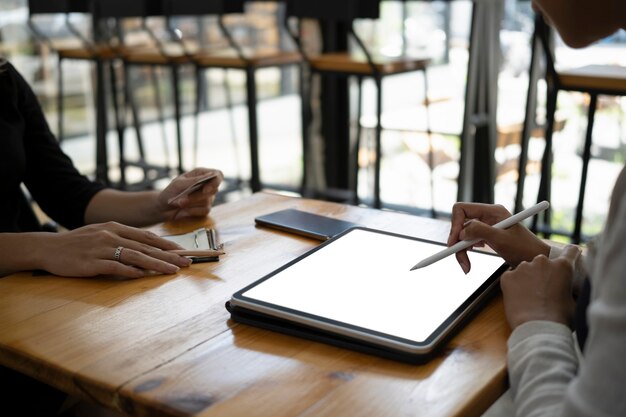 Cropped schoss zwei Geschäftskollegen, die gemeinsam im Büro Geschäftsdaten auf einem digitalen Tablet besprechen.