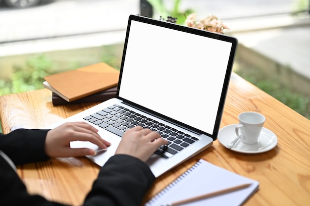 Croppped schuss der geschäftsfrau mit laptop mit weißem bildschirm auf holztisch.