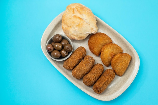 Croquet de carne de aperitivo típico portugués en el plato sobre papel azul