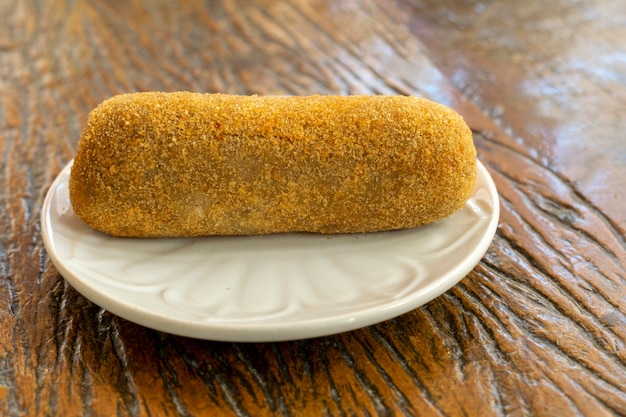 Croqueta de carne en un plato blanco sobre fondo de madera rústica