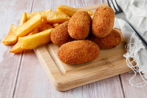 Croquetas caseras con astillas sobre tabla para cortar madera