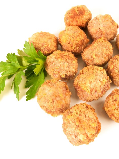 Croquetas y hojas de perejil sobre un fondo blanco.