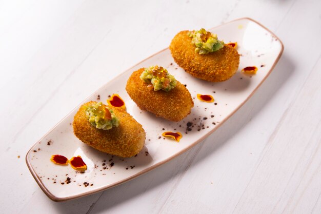 Croquetas de jamón ibérico con guacamole por encima. Tapa española moderna.