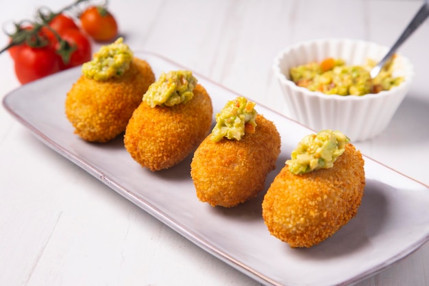 Croquetas de jamón ibérico con guacamole por encima. Tapa española moderna.