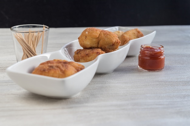 Croquetas de queso preparadas como una tapa para tomar con salsa de tomate.