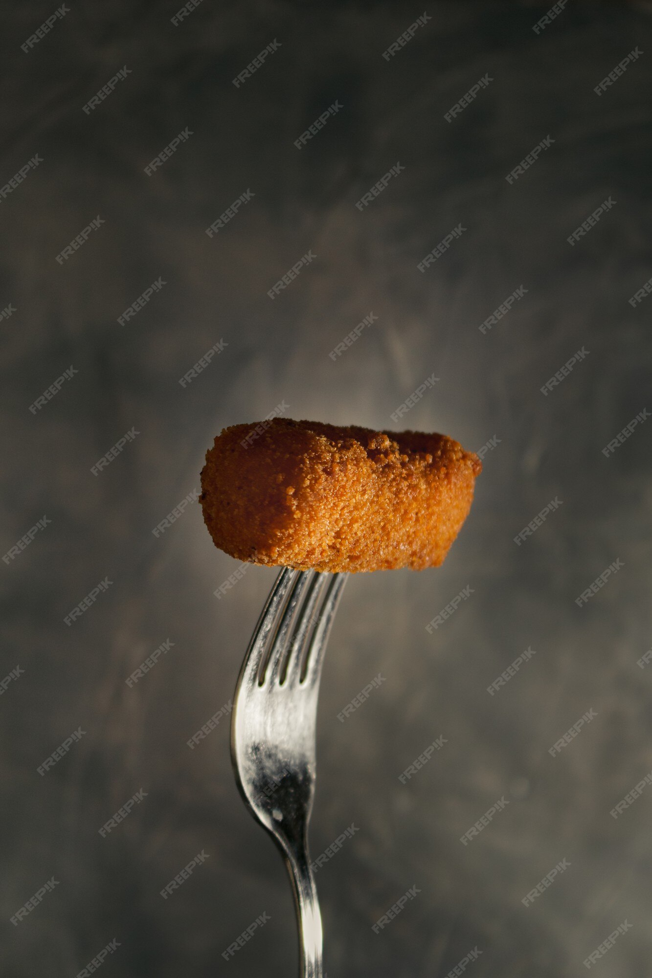 Croquete caseiro tradicional espanhol no garfo com fundo escuro