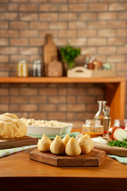 Foto croquete de frango brasileiro coxinha de frango em uma mesa de madeira e um fundo de cozinha de tijolos