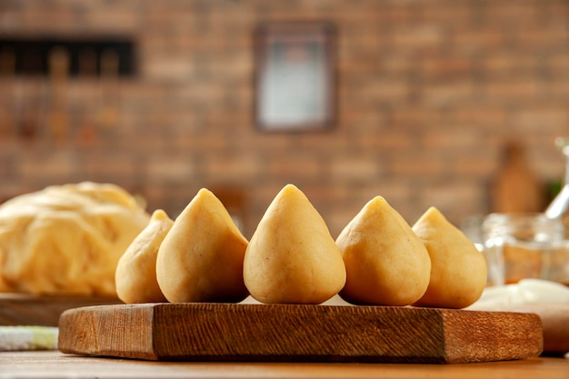 Croquete de frango brasileiro coxinha de frango em uma mesa de madeira e um fundo de cozinha de tijolos