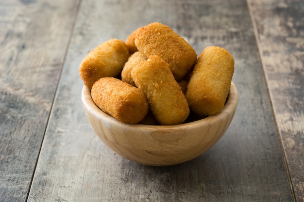 Croquetes espanhóis fritos tradicionais (croquetes) na tigela sobre fundo de madeira