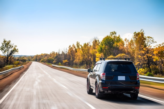 Crossover negro moviéndose en la carretera en otoño