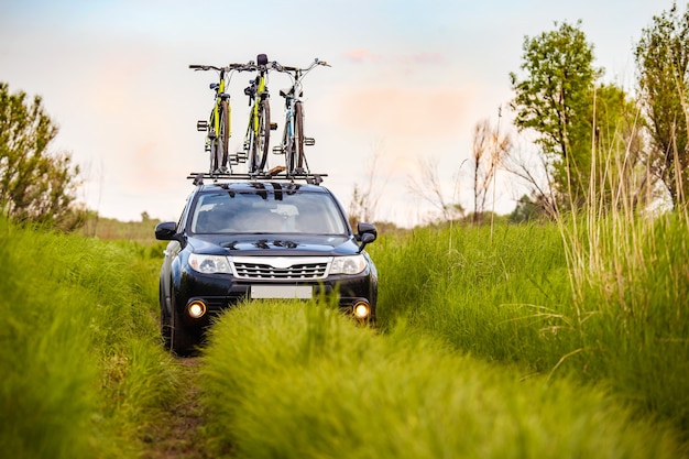 Crossover negro con tres bicicletas en la baca en una pradera