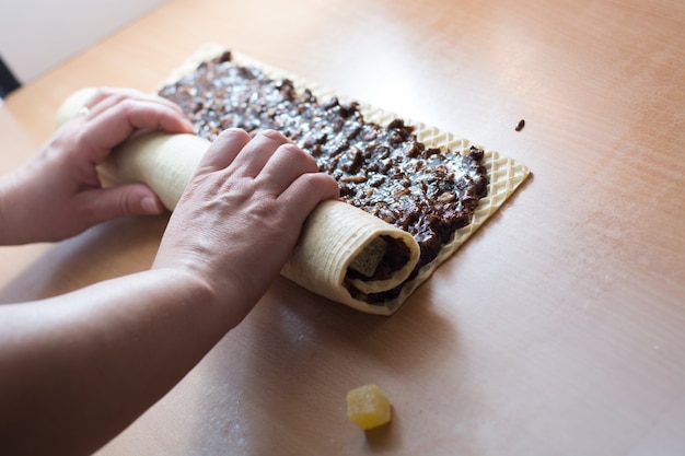 Crosta de bolo rolando com bombons de chocolate e geleia. Preparando para cortar com faca