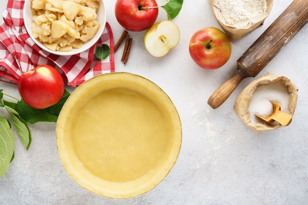 Crosta de torta enrolada em uma assadeira com ferramentas e ingredientes