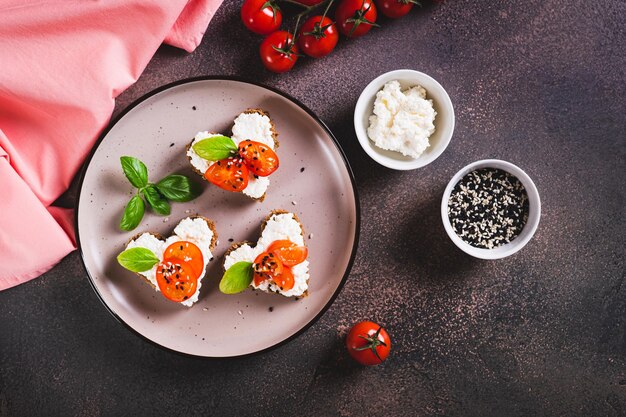 Crostini apetitoso em pão de centeio em forma de coração com ricotta e tomates vista de cima