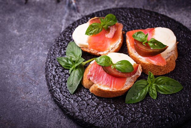 Crostini com salmão, mozarella, tomate e manjericão