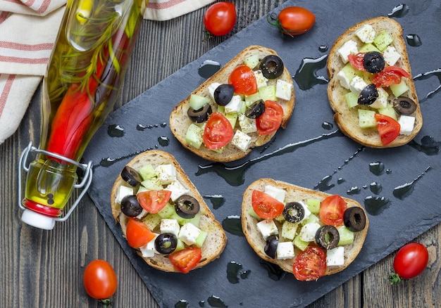 Foto crostini de estilo griego con queso feta tomates pepinos aceitunas y hierbas vista de arriba