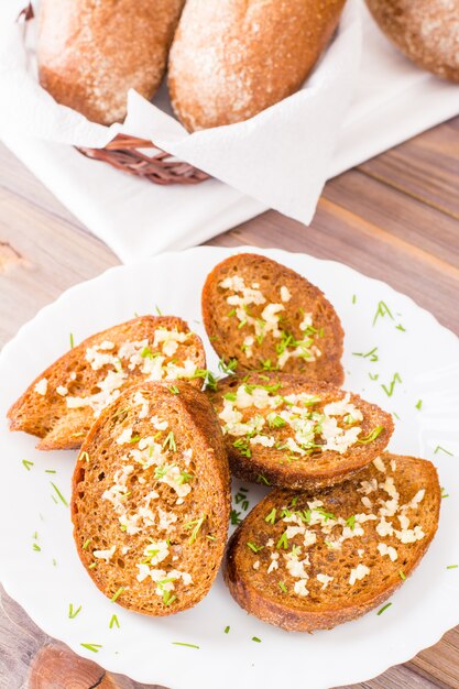 Croutons de alho fresco centeio com endro em um prato sobre uma mesa de madeira