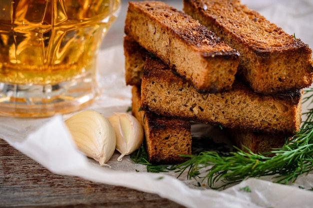 Croutons de centeio e cerveja light em uma caneca de vidro sobre uma mesa de madeira