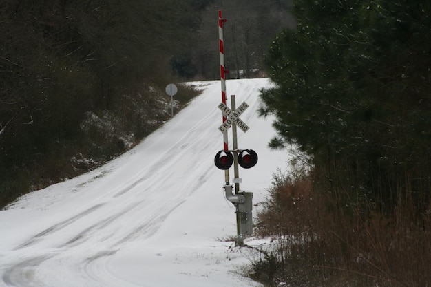 Cruce de ferrocarril en una carretera cubierta de nieve en medio de árboles