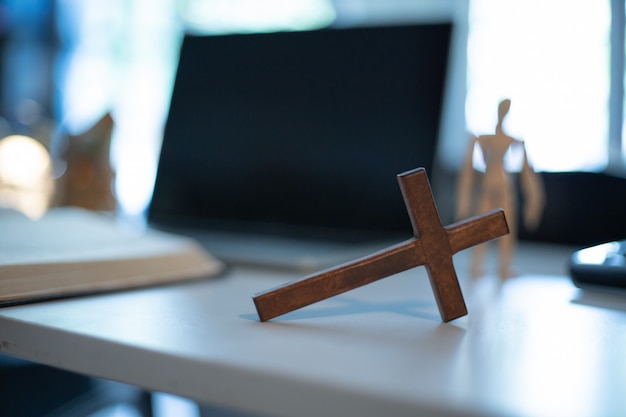 Cruce la mesa de madera con luz de ventana. concepto de iglesia en línea.