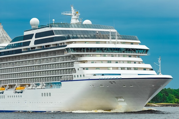 Crucero blanco moviéndose hacia el mar en día nublado