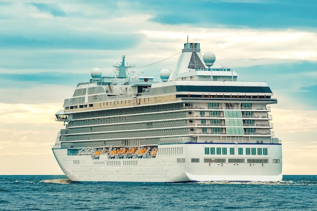 Crucero blanco moviéndose hacia el mar en día nublado