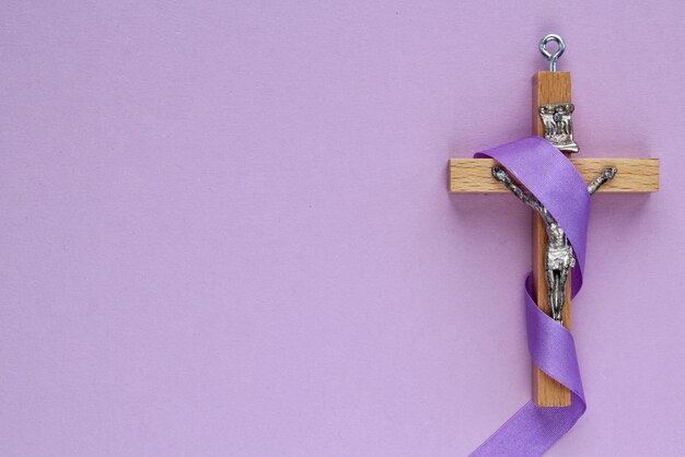 Crucifixo de cruz de madeira religiosa cristã com fita violeta na religião católica de fundo roxo