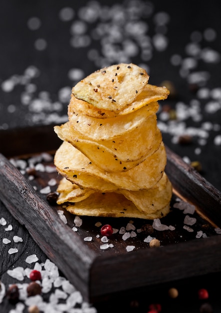 Crujientes deliciosas patatas fritas de patatas fritas snack sobre tabla de madera oscura y sal