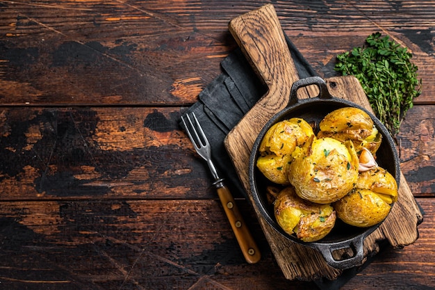 Crushed Broken Potatoes gebacken in Öl mit Kräutern Holzhintergrund Ansicht von oben Kopieren Sie Platz