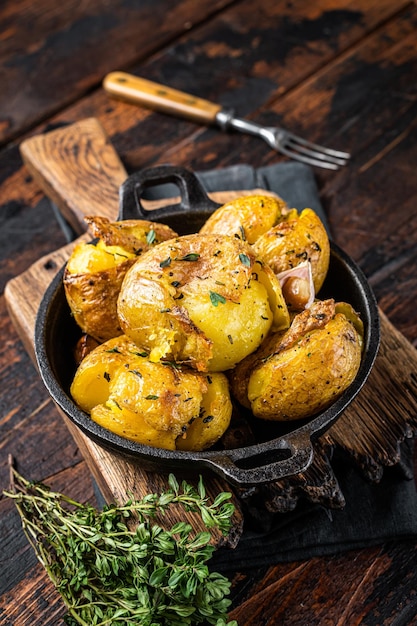 Crushed Broken Potatoes gebacken in Öl mit Kräutern Holzhintergrund Ansicht von oben