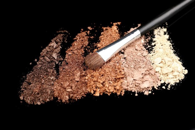 Crushed Lidschatten und professionelle Make-up-Pinsel isoliert auf schwarz