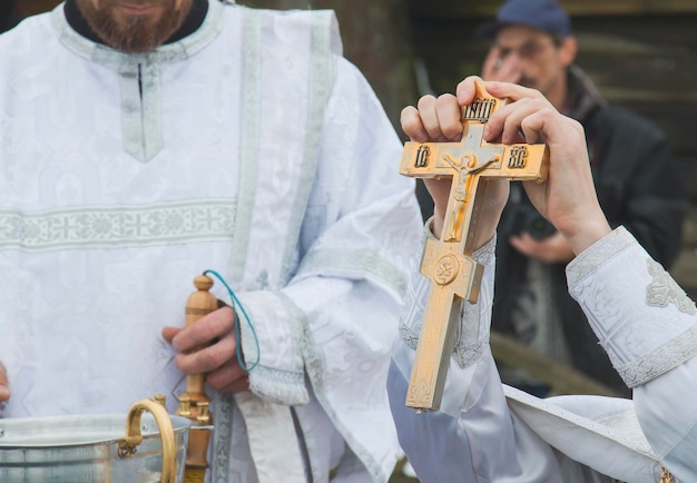 Foto cruz de bautizo sobre el agua un padre lee la oración