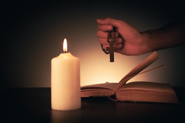 Cruz con biblia y vela en una mesa de madera