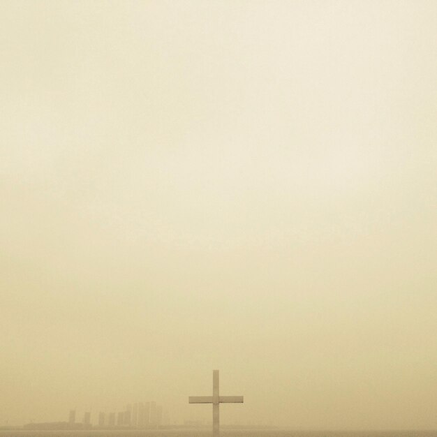Cruz contra el cielo despejado durante el tiempo de niebla