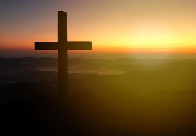 Cruz cristã de silhueta na grama no fundo do nascer do sol