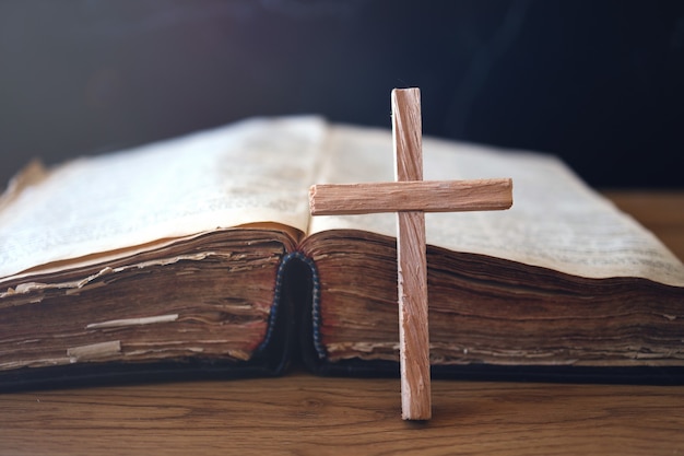 Cruz cristiana de madera sobre la Santa Biblia sobre mesa de madera