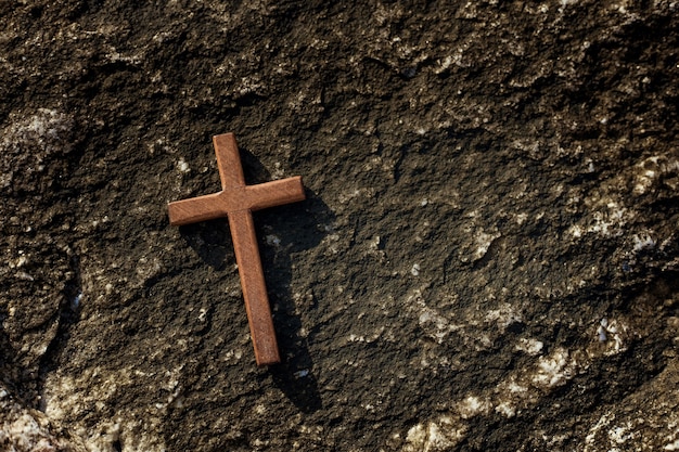 Cruz de madeira com fundo de pedras.