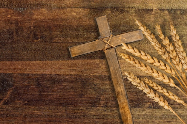 Cruz de madeira e trigo dourado na mesa