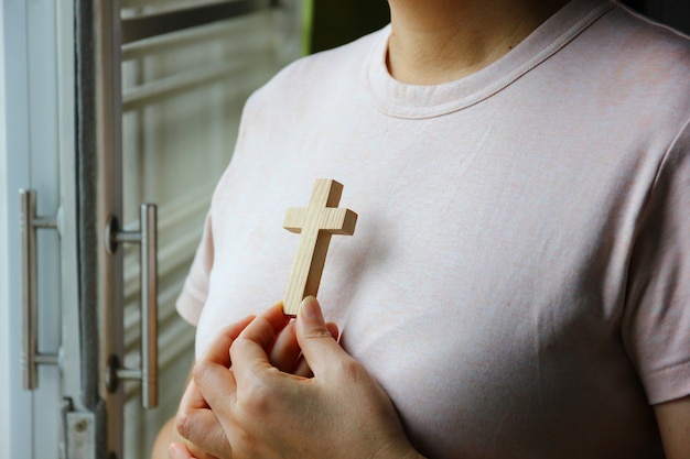 Cruz de madeira na mão da mulher contra o peito